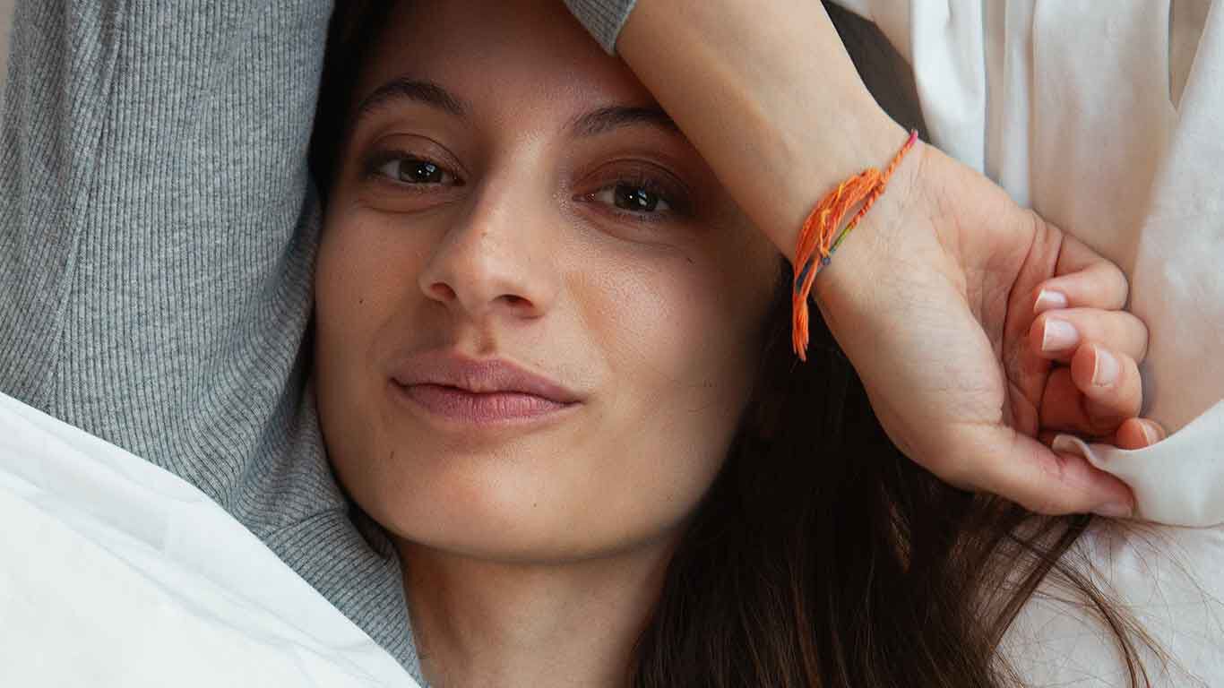 Gros plan sur une femme allongée dans son lit, détendue. 